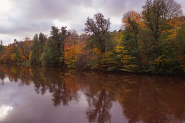 River lined with colorful trees in autumn, reflecting in the water in Sweden.