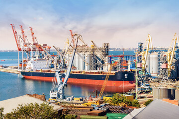 Naklejka premium Cargo ship at the dock. Cranes and colored containers at the port.