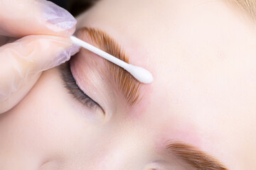the master smoothes and removes excess eyebrow makeup with a cotton swab