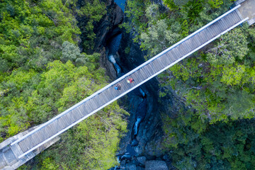 Aerial view of two persons hiking in the mountain crossing an off trail bridge near La Possession, Saint Paul, Reunion.