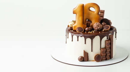 Birthday cake with chocolate drips decorated with chocolate cookies. Happy 18 years old. reaching age of majority. Gingerbread cookies with golden icing in the shape of digits one and eight.