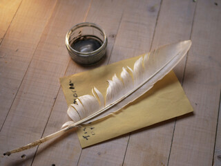 Quill and ink on wooden desk with parchment paper 