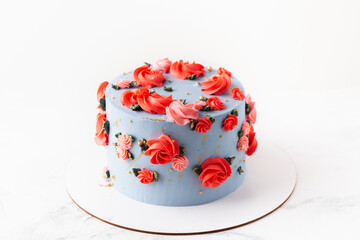 Birthday cake with blue cream cheese frosting decorated with red flowers on the white background. Happy 70 years anniversary
