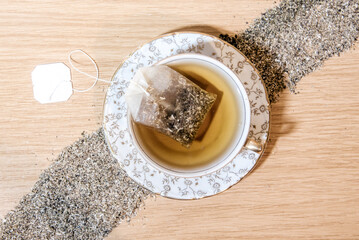 Vista cenital de una taza de té con una bolsita de té de manzanilla en el interior. Hierbas secas...