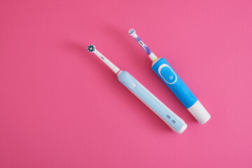 two electric blue toothbrushes on bright pink background oral hygiene concept