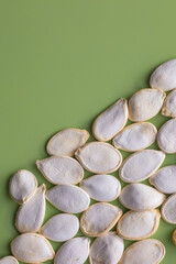 A composition of healthy pumpkin seeds in a shell on a green background for a healthy diet.