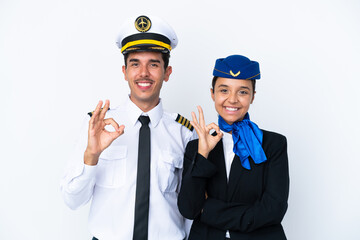 Airplane pilot and mixed race air hostess isolated on white background showing an ok sign with...