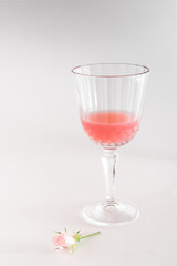 Champagne glass of grapefruit juice with pink rose. Minimal modern concept. Creative copy space.