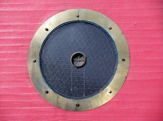 Porthole round ventilation window on red wall
