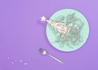 Abstract silver dessert composition. Silver Christmas tree and silver decorative spaghetti is placed on a stylish plate. The mixture of pastel mint, silver, and pastel purple colors is eye-catchy.
