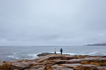 Fototapeta na wymiar A couple of young people watching at the coastline nearby russian village Teriberka, Murmansk region