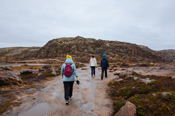 Fototapeta premium A Group of Young Friends Walking up a Mountain Path in the vicinity of Teriberka at sunrise