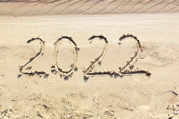 New Year 2022. Message written on the background of a sandy beach. hello concept for the upcoming new year 2022. New Year Christmas. with copy space for text. Close-up and top view of shiny