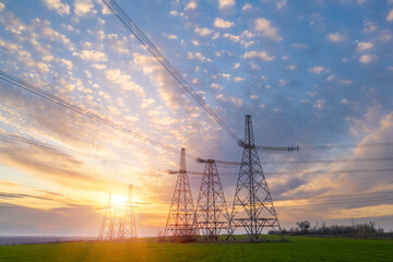 power line pylons during sunset with beautiful saturated sky. distribution transmission and consumption of electricity