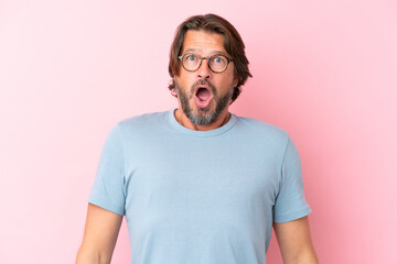 Senior dutch man isolated on pink background With glasses and surprised expression