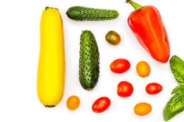 Vegetable flatlet: cucumbers, zucchini, cherry tomatoes, a sprig of basil and peppers on a white plate.