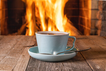 A cup of tea or coffee before a cozy fireplace, in a country house.