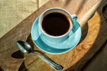 Cup of coffee on a board,illuminated by sunlight , autumn day.