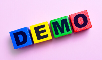 On a light pink background, multi-colored wooden cubes with the text DEMO