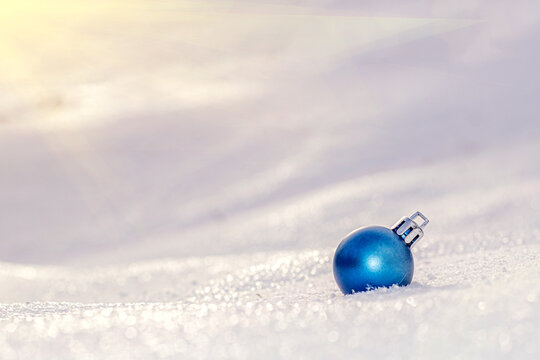 one blue christmas tree ball on white snow