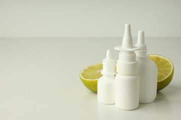 Blank bottles of nasal spray and lime halves on white table