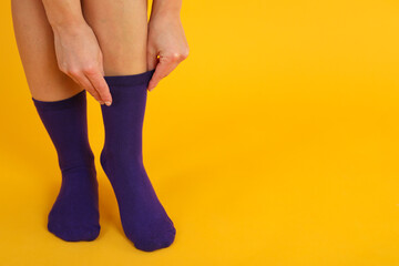 Woman pull up socks on yellow background