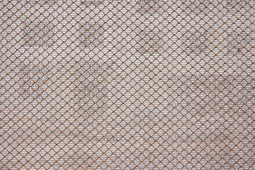 Fototapeta premium Fragment of a fence made of rusty metal mesh. In the background, a wall of a house under construction with windows is visible through a screen made of synthetic canvas. Background. Texture.