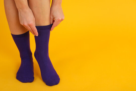 Woman Pull Up Socks On Yellow Background