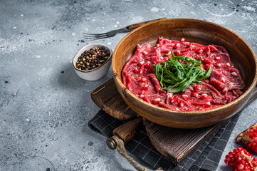 Classic beef meat carpaccio with arugula and pomegranate seeds. Gray background. Top view. Copy space