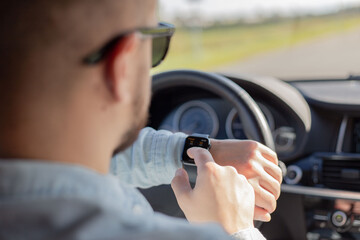 close up of a man using his smart watch while sitting in a car.
