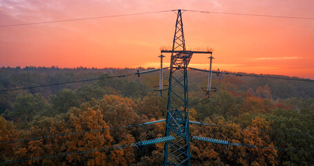 Obraz premium Power line pylon, on a background of sunset and forest.