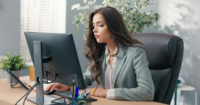 Busy businesswoman sits at desk in front of the computer in the office, she has technical problems with the monitor, wrong screen setting, no signal, error, the woman laughs can not do the work
