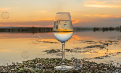 Vue d'un verre à vin avec un coucher de soleil sur les parcs à moules d'un étang de la Camargue, réserve naturelle protégée