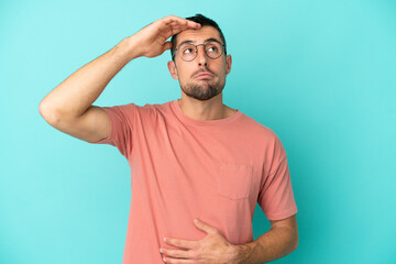 Fototapeta na wymiar Young handsome caucasian man isolated on blue background With glasses and tired