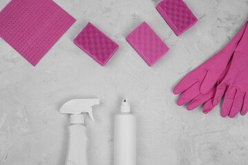 Cleaning and disinfection products agent, sponges, napkins and rubber gloves in pink colors on stone gray background top view copy space. Household cleaning products.