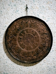 A bronze metal antique plate with hand-minted coinage hangs on a white wall in the Dagestani village of Harbuk
