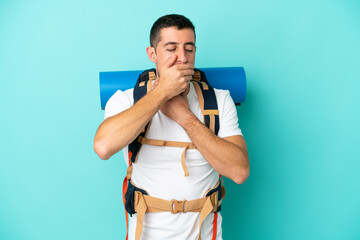 Young mountaineer caucasian man with a big backpack isolated on blue background is suffering with cough and feeling bad