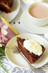 Chocolate plum cake with whipped cream, served with cocoa. Rustic style.