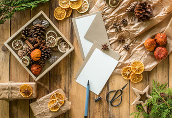 Weihnachten leere Grußkarte und Briefumschlag. Festliche Weihnachtsdekoration natürlich gestaltet mit Orangenscheiben, Zapfen, Anis auf Packpapier und Holzuntergrund