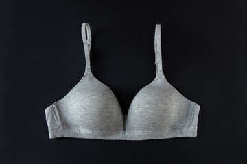 Gray organic or recycled cotton bra on black background, top view, copy space, flat lay. Concept of femininity, comfort, home clothes, underwear, natural textile, minimal style. Horizontal