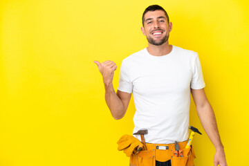 young electrician caucasian man isolated on yellow background pointing to the side to present a...