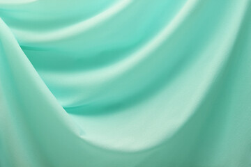 turquoise material flows in soft folds background