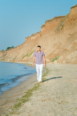 guy in white trousers walks along the seashore against