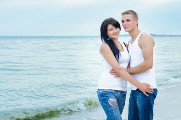 guy and a girl in jeans and white t-shirts on the beach