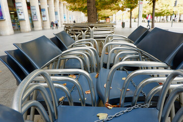 Chairs stacked in piles on a summer terrace of a street restaurant, cafe. Outdoors leisure place ready to close in Zaragoza, Spain