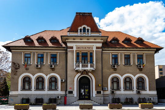 Bacau, Romania, May 02, 2021: Photo in front of the symmetrical Post Office building, which has 2 Romanian flags on the windows