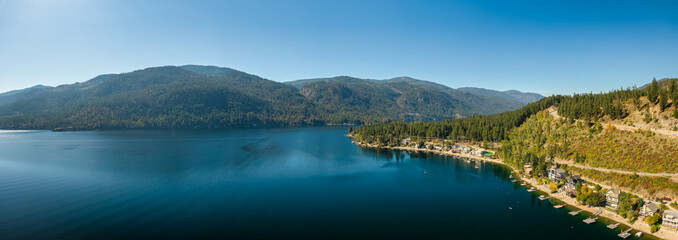 Aerial panoramic view of a residential homes by a lake and mountains. Christina Lake, East...