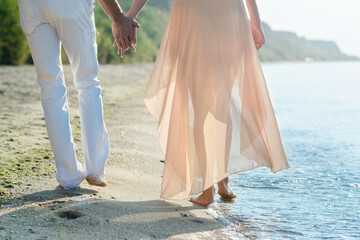 a guy and a girl walk along the seashore