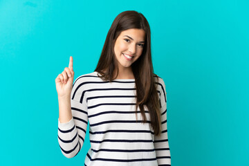 Teenager Brazilian girl over isolated blue background showing and lifting a finger in sign of the best