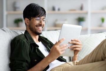 Relaxed middle-eastern young man chilling at home with digital tablet